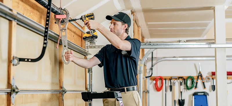 Technician performing preventative maintenance on a garage door in San Antonio, including lubrication and hardware tightening.